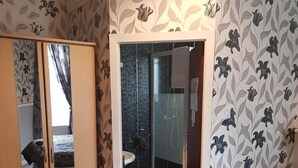 A bedroom with a bed, a wardrobe, and a bathroom with a shower and sink. - Thornhill Blackpool (Blackpool)