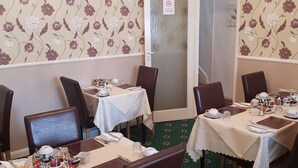 A dining area with floral wallpaper, a chandelier, and a 'No Smoking' sign on the door. - Thornhill Blackpool (Blackpool)