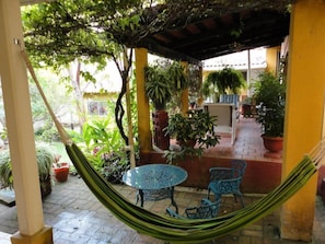 A covered outdoor area with a hammock, a round table, and blue chairs. - La Posada de Juan B&B (Santa Rosa Copan)