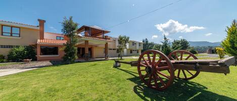 A house with a large lawn and a wooden cart.