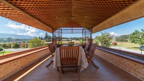 A covered outdoor patio with a table and chairs, offering a view of the surrounding landscape. - Hacienda Grande Hotel (San Cristóbal Totonicapán)