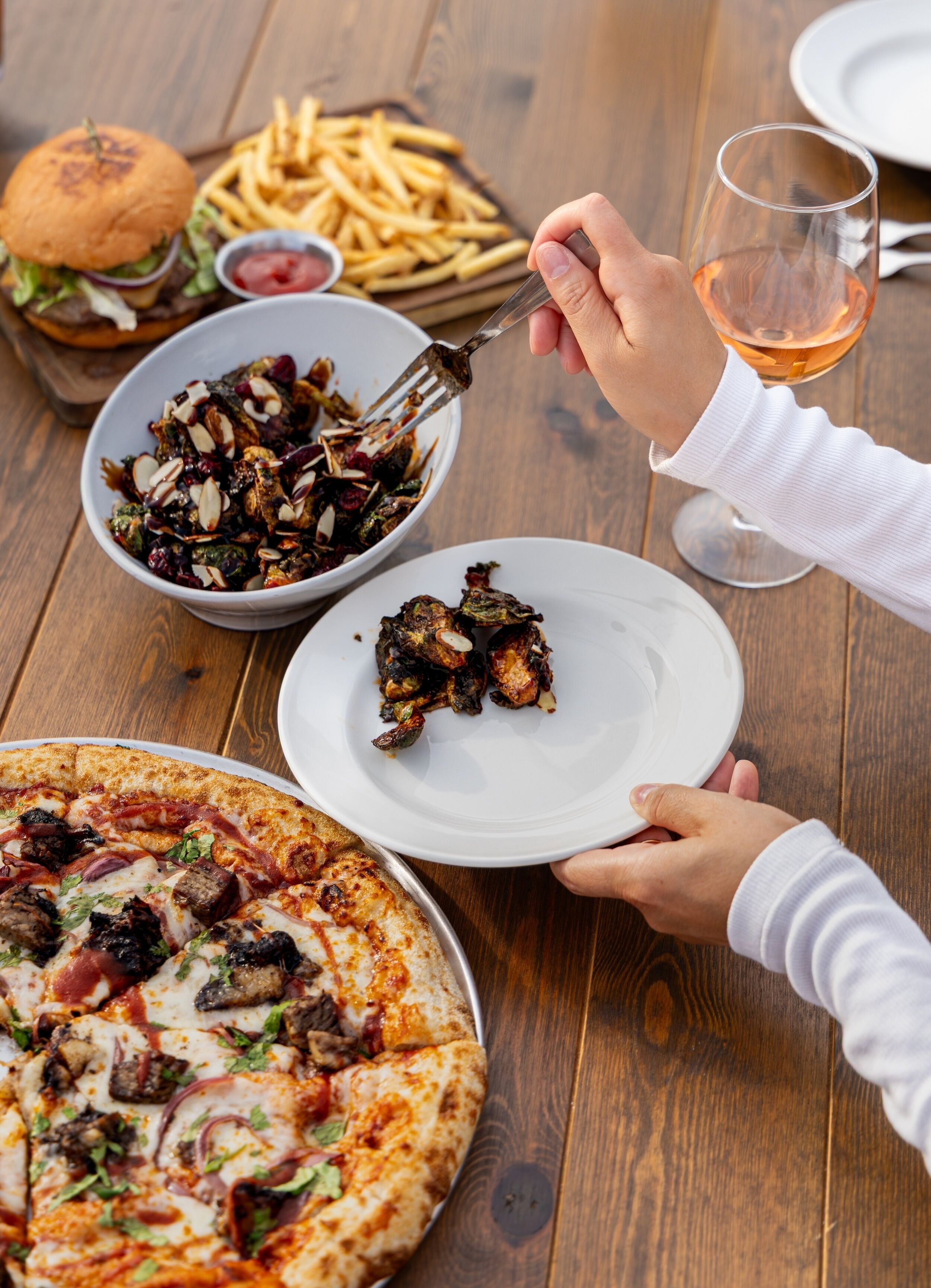 A dining table with a pizza, a burger, fries, and a salad.