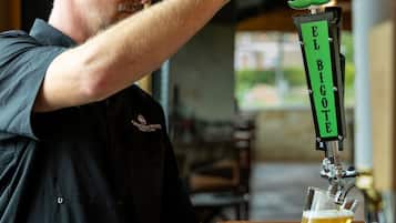 A person pouring beer from a tap labeled 'EL BIGOTE' into a glass.