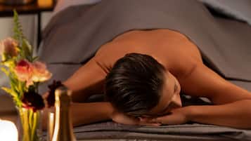 Experience a serene spa setting with a massage table, wine, and fresh flowers.