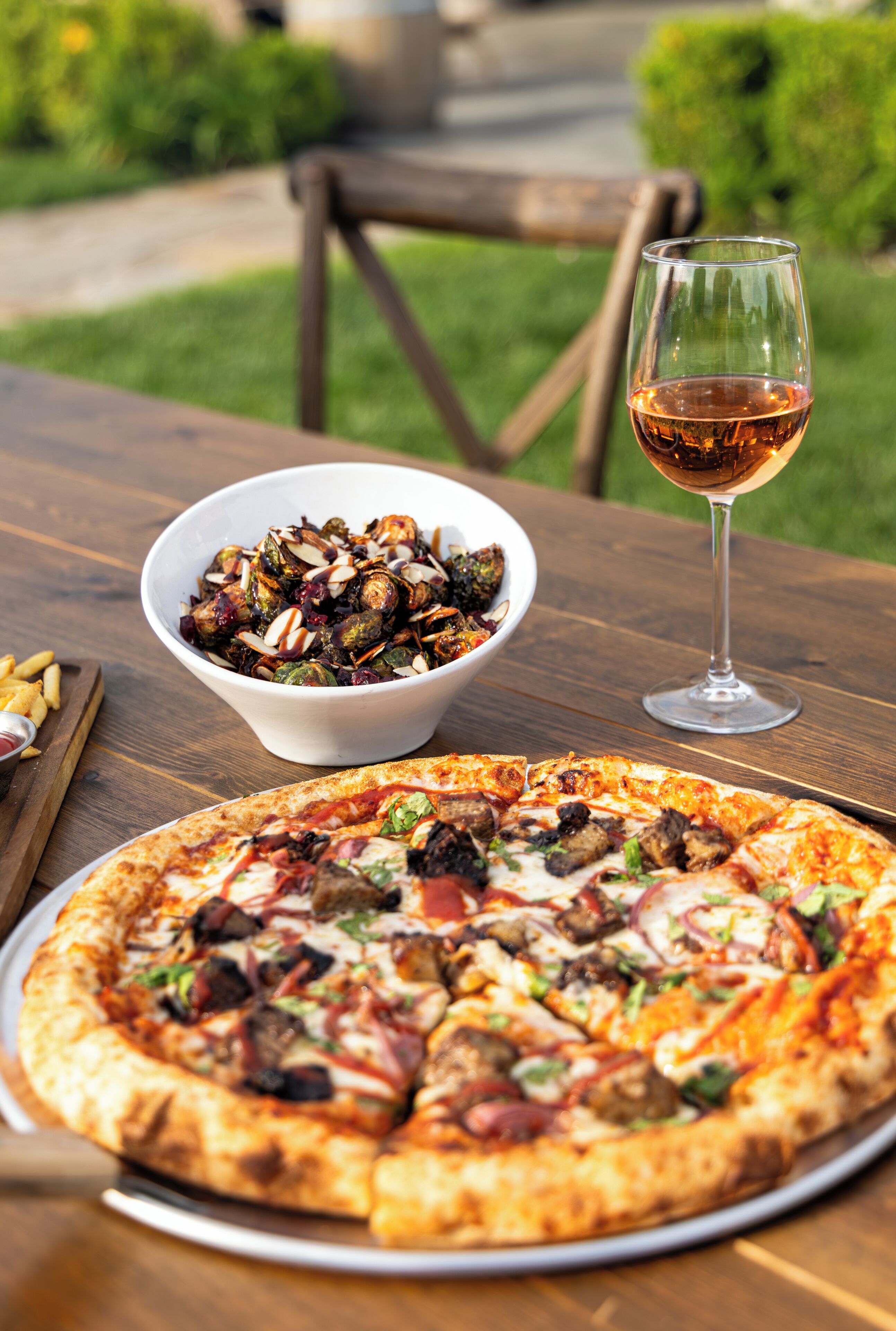 A pizza and a bowl of food on a wooden table.