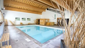 Una piscina con bancos y sillones de madera, techo de madera y suelo de baldosas.