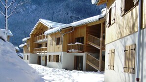 Un chalet de madera con balcones y un sendero cubierto de nieve.