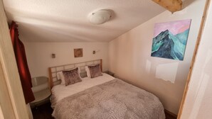 Ein Schlafzimmer mit einem Bett, einem Bild an der Wand und einer Deckenleuchte.