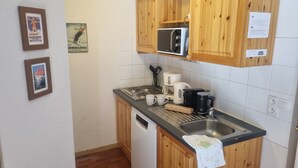 Eine kleine Küche mit Holzausstattung, einer Mikrowelle, einer Kaffeemaschine und einem Geschirrspüler.