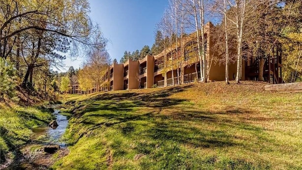 Un immeuble doté de nombreux balcons, d’une zone verdoyante et d’un ruisseau.