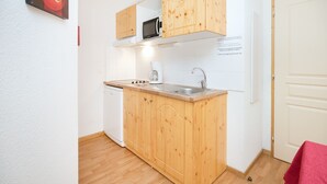 Uma cozinha compacta com armários de madeira, micro-ondas, cafeteira e lava-louças.