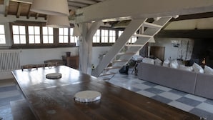 Un comedor rústico con una mesa de madera, una escalera y un sofá.