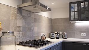 Una cocina moderna con estufa a gas, tostadora, hervidor y un armario con puertas de vidrio.