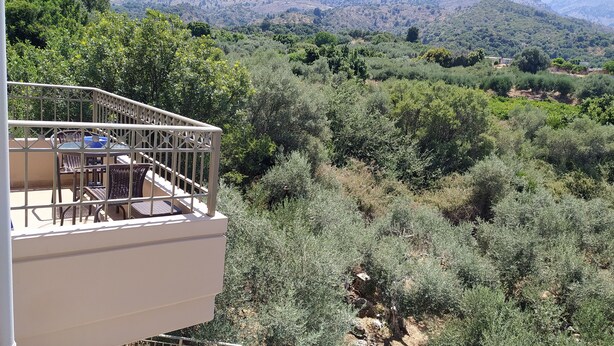Balcón con mobiliario exterior que ofrece vistas a un paisaje montañoso y una piscina.