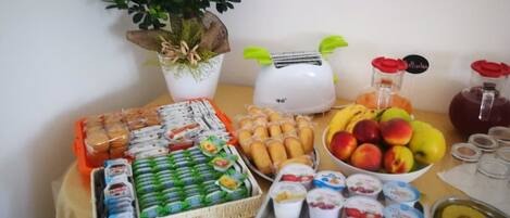 A buffet table with various food items, including fruits, pastries, and dairy products.