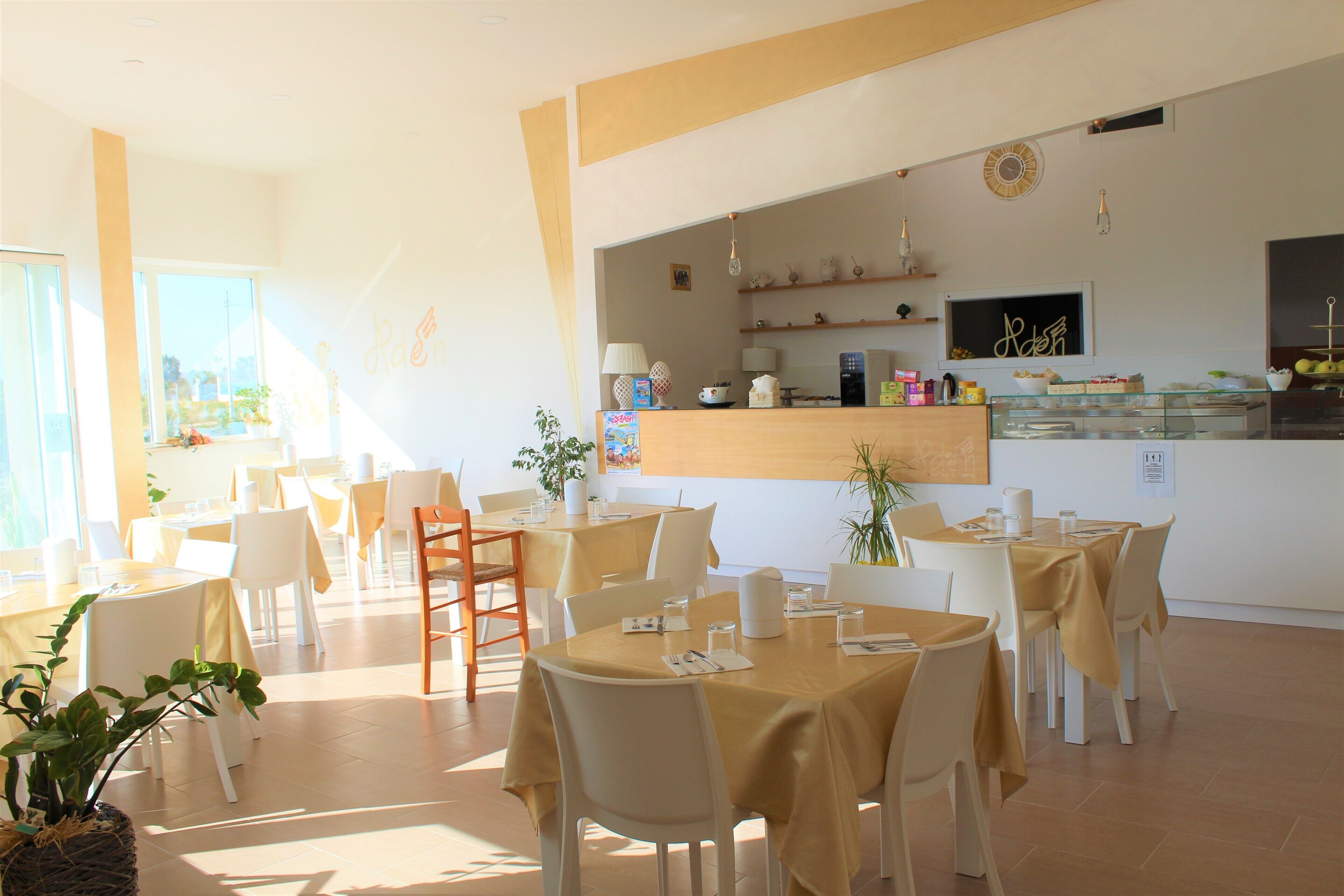 Un restaurante con mesas redondas, sillas y una barra con una exhibición de alimentos.