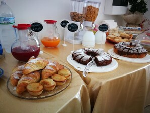 A buffet table with various food items including pastries, a cake, and a fruit punch. - Aden B&B Salento (Sannicola)