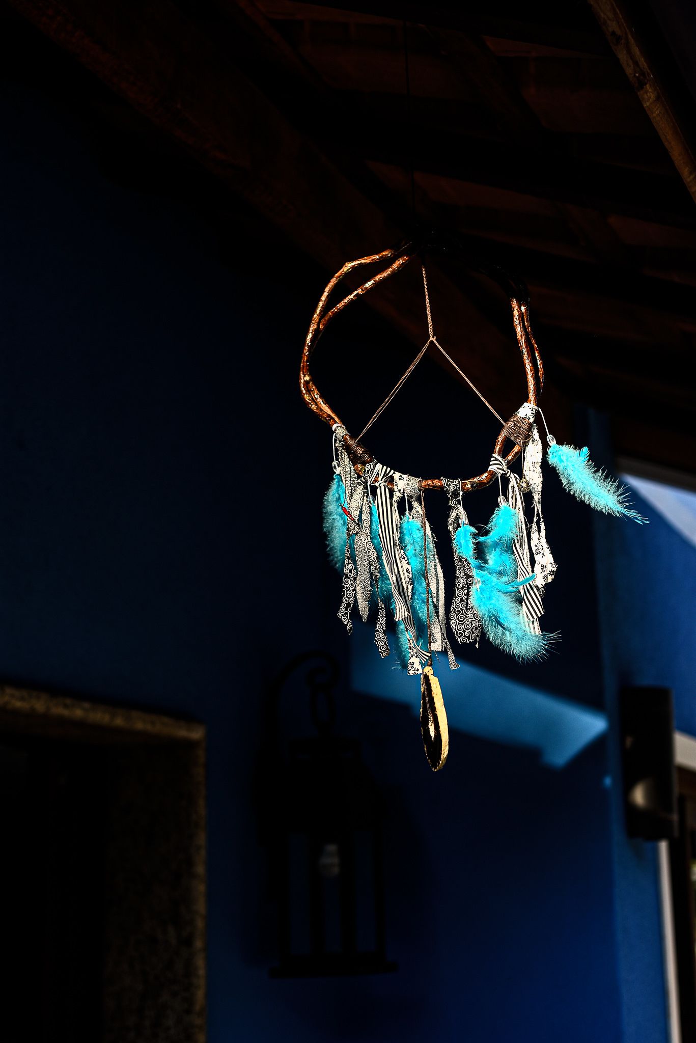 Un atrapasueños con plumas y diseños colgando del techo de madera.