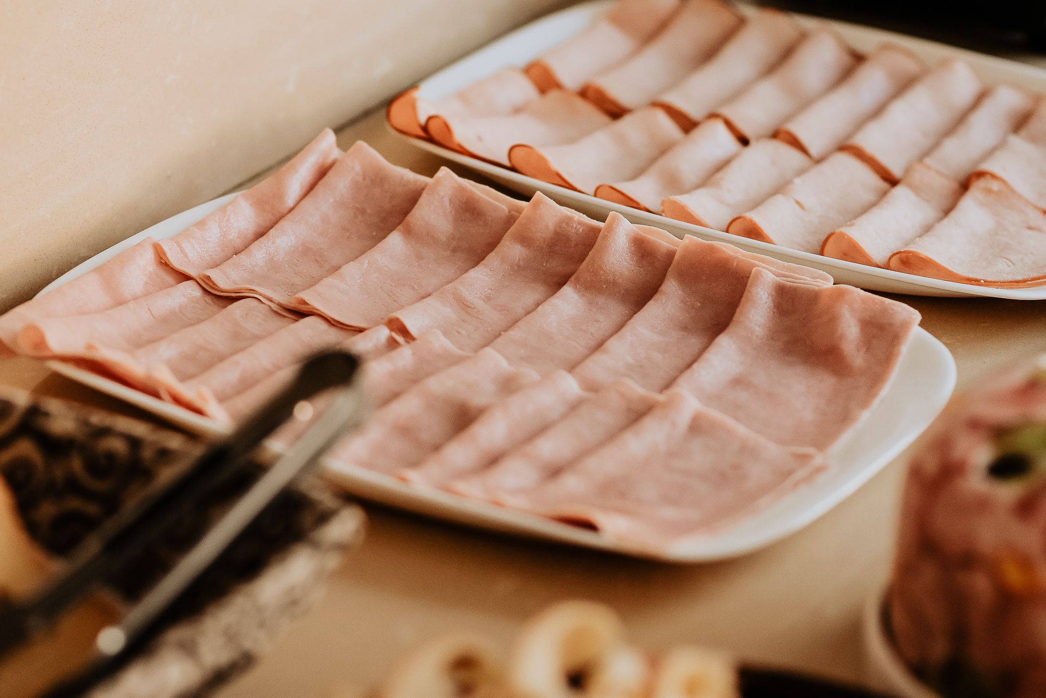 Neatly arranged plates of sliced meat on a table.