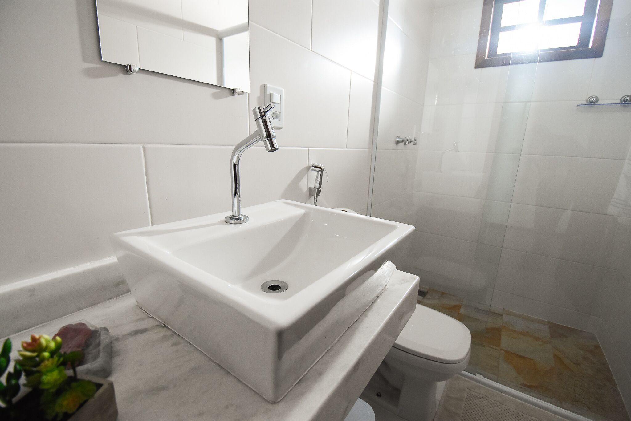 A bathroom with a white sink, a mirror, and a toilet.
