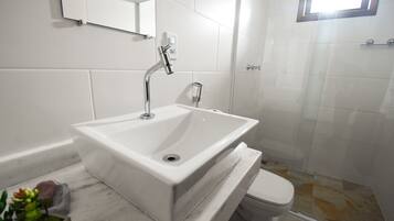 A bathroom with a white sink, a mirror, and a toilet.