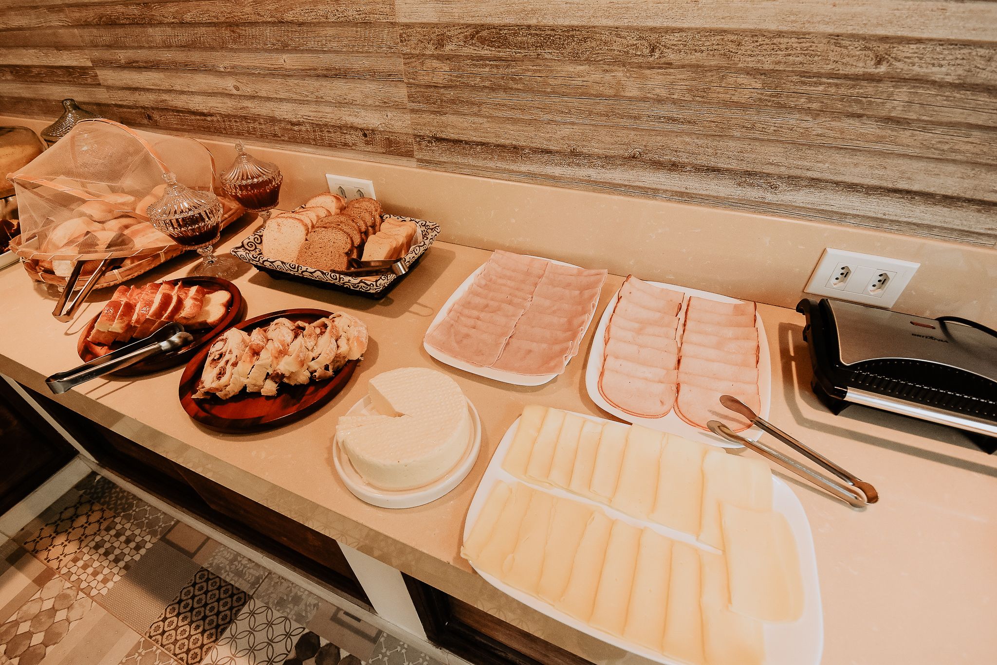 Una mesa de buffet con diversos alimentos, entre ellos pan, pasteles y un pastel.
