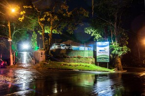 A nighttime view of a gated area with a sign for "Paris Hostelli" and a building in the background. - Pousada Paris Hostelli (Itatiaia)