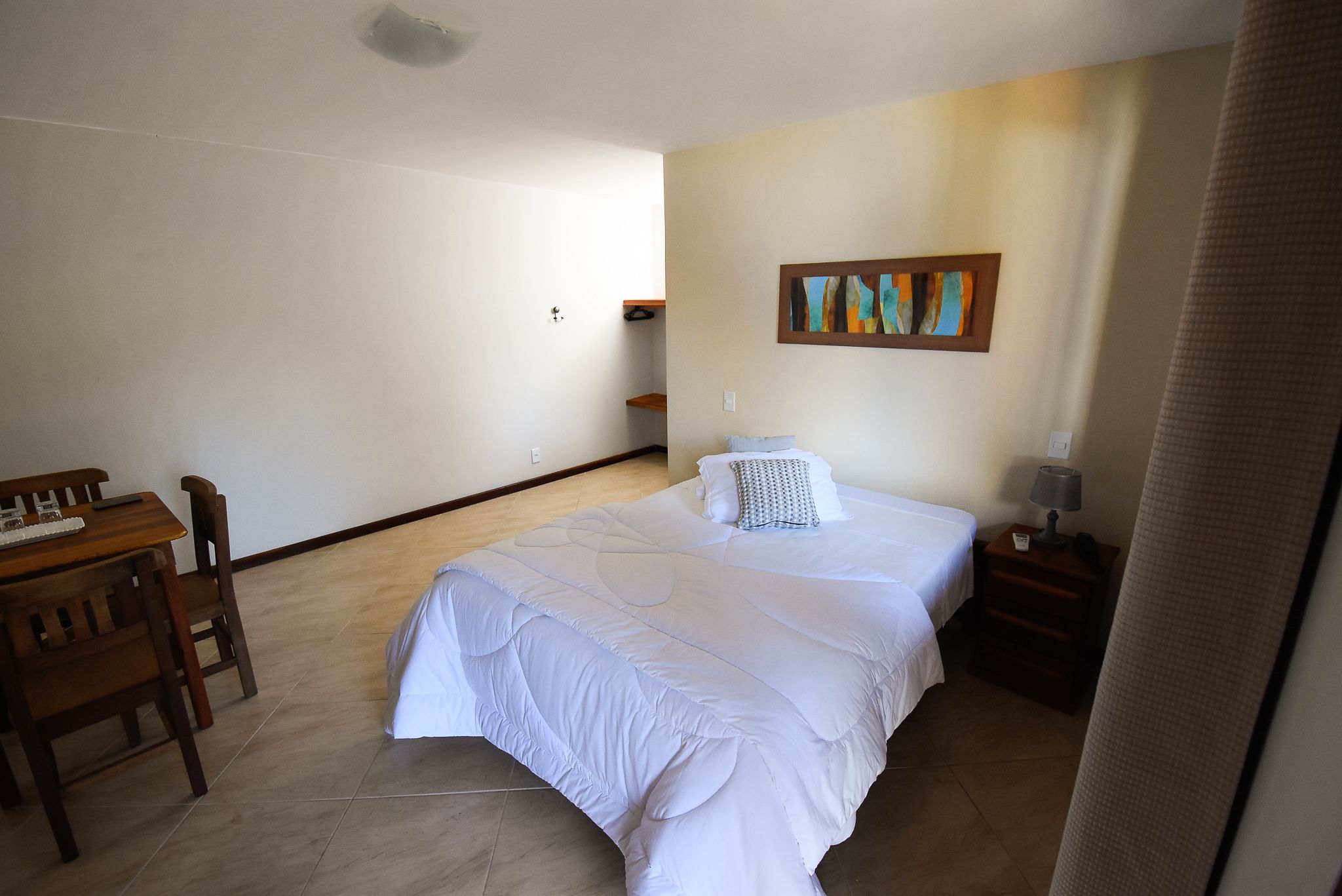 A bedroom with a large bed, a desk, and a chair.