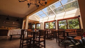 Un restaurante con techo alto, ventanas amplias y mobiliario de madera.