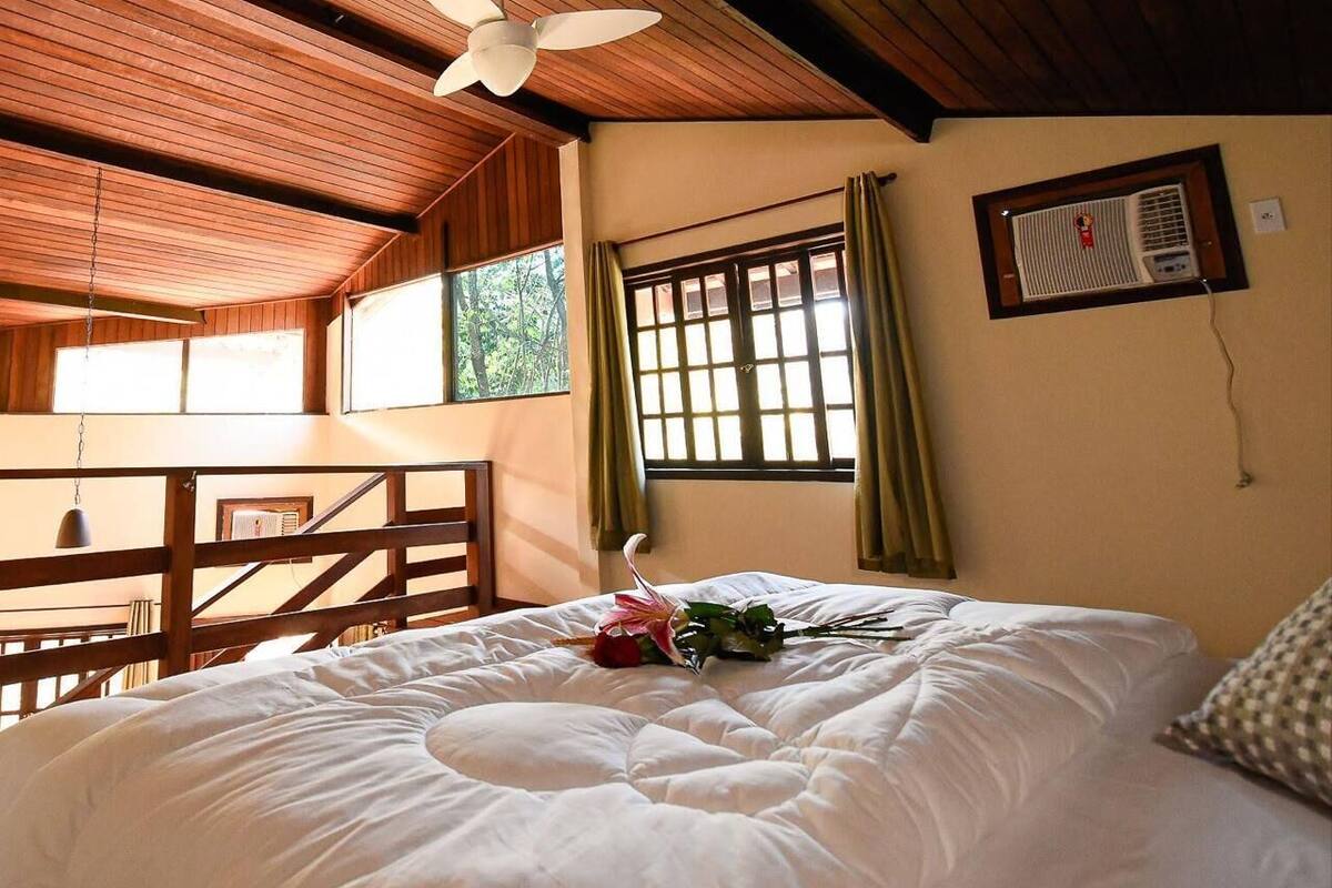 A bedroom with a bed, a ceiling fan, a window with curtains, and a table with chairs.