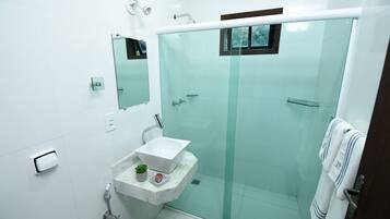 Une salle de bain moderne avec une douche en verre, un lavabo en marbre et une petite plante en pot.