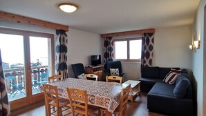A spacious living area with a dining table, chairs, a sofa, and a television.