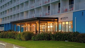 Ein Hotel mit überdachter Außenbestuhlung, blauem Äußeren und einem Schild mit der Aufschrift 'RANCSA'.