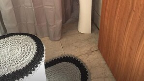 Ein Badezimmer mit einem weißen Waschbecken, einer Holztür und einem beigefarbenen Vorhang.