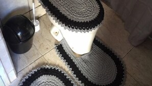 Ein Badezimmer mit Toilette, einem schwarzen Mülleimer und einer weißen Toilettenbürste.