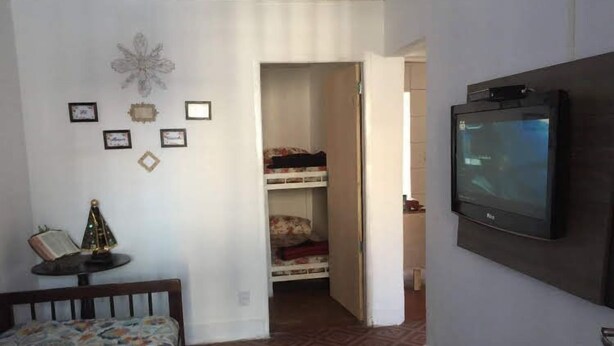 Ein Schlafzimmer mit Bett, Fernseher, Kleiderschrank und einem kleinen Tisch mit einem dekorativen Gegenstand.