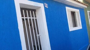 Ein blaues Gebäude mit zwei Fenstern, eines mit vergittertem Glas und das andere mit Fensterläden.
