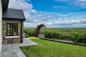 Stunning home with a large window and inviting porch, set amidst a beautifully manicured lawn and vibrant flower bed.