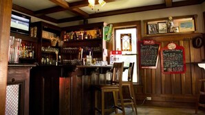 A bar area with wooden beams, a television, shelves with bottles, and a chalkboard menu. - Distinctive Inns of Kingsville Inn31 (Kingsville)