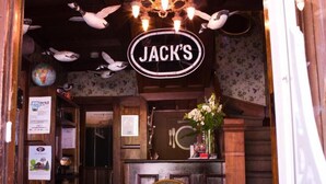 A restaurant entrance with a neon sign reading "JACK'S" and a chalkboard sign that says "PLEASE WAIT TO BE SERVED". - Distinctive Inns of Kingsville Inn31 (Kingsville)