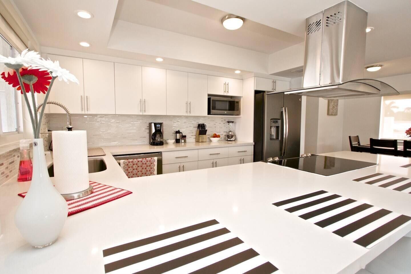 A modern kitchen with white cabinetry, stainless steel appliances, and a central island with striped patterns.