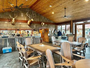 A rustic interior with wooden tables and chairs, a bar area, and mounted animal heads on the wall.