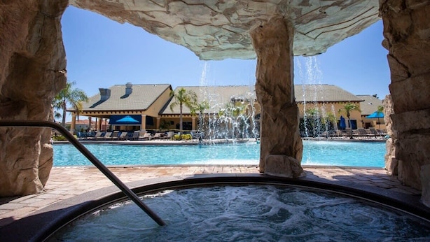 A hot tub with a view of a pool and a building with a tiled roof. - Three King Suites & Private Pool! 5BR Near Disney (Kissimmee)