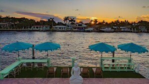 Una vista tranquila del frente marítimo con una estatua de Buda, sillas de descanso y sombrillas.