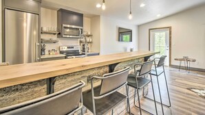 Eine moderne Küche mit Bar, Edelstahlgeräten und einer Steinrückwand.