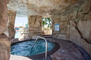 Un espace spa comprenant un bain à remous, des murs en pierre et un panneau indiquant les règles à respecter dans le spa.