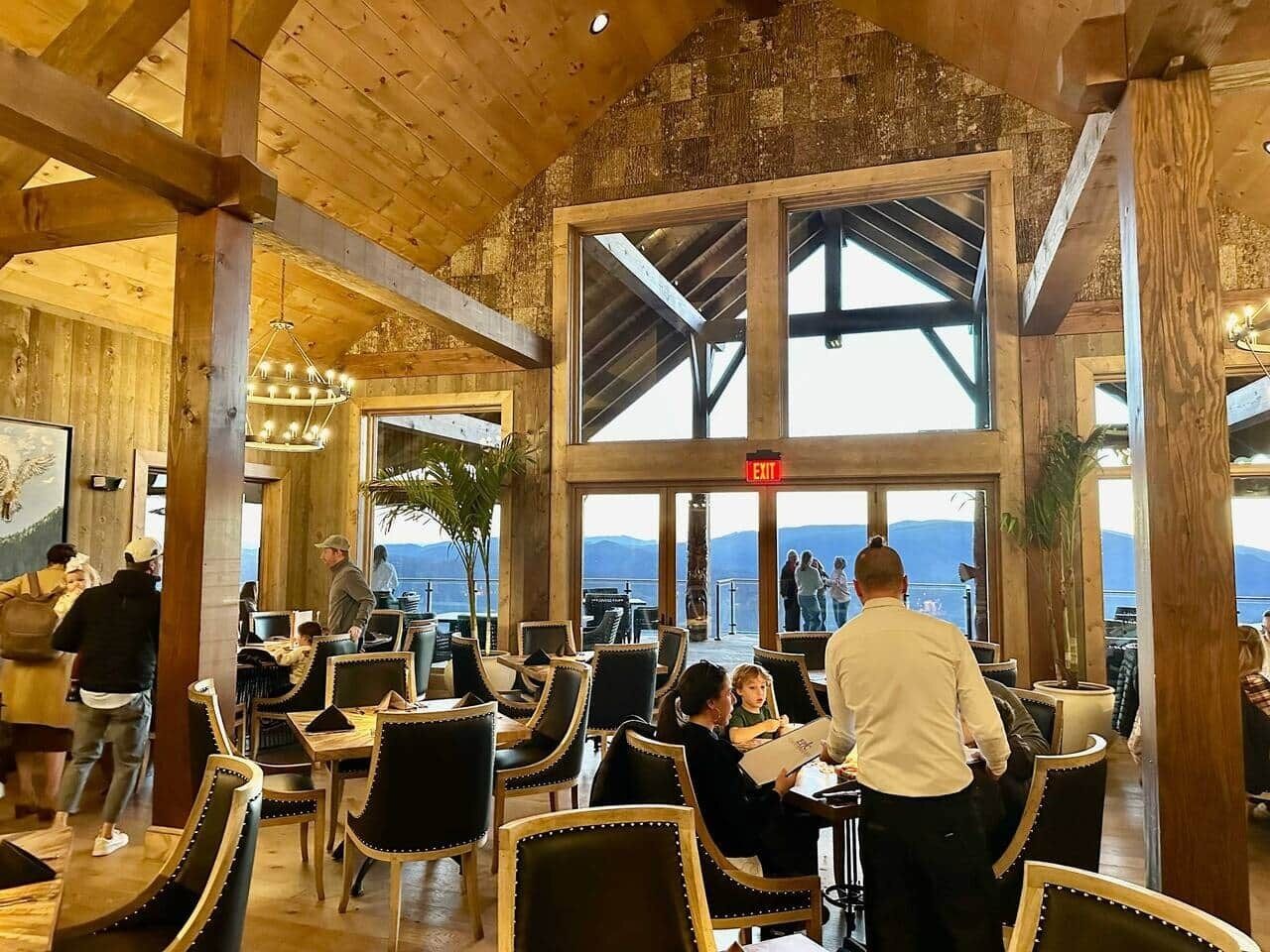 Un restaurant avec des poutres en bois, de grandes fenêtres et une vue sur les montagnes.