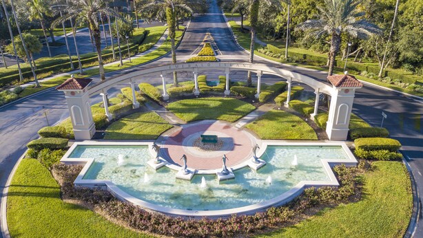 A circular fountain with a central seating area, surrounded by a landscaped garden with palm trees and a paved walkway. - "The Beauty", a SPLENDID Townhome Near Disney - Free WiFi, sleeps 8 comfortably! (Kissimmee)