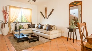 Una sala de estar con sofá, mesa de centro y un espejo grande.