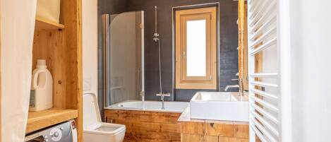 A compact bathroom with a wooden vanity, a toilet, a shower enclosure, and a built-in sink.